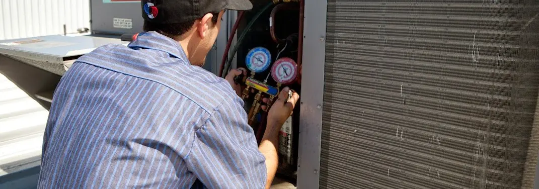 HVAC technician servicing a condenser unit in Wooster